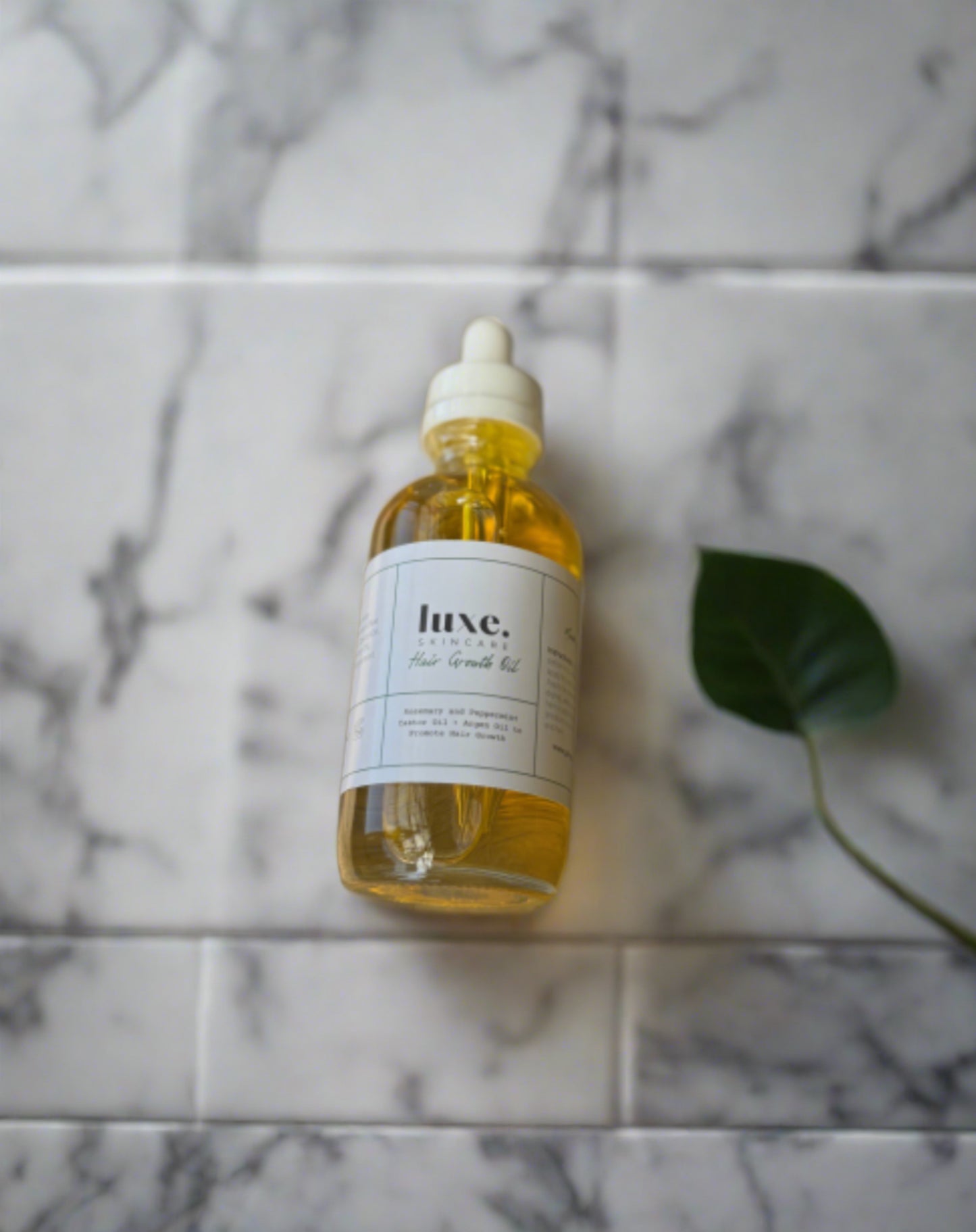 Hair growth oil against a marble tile background. 